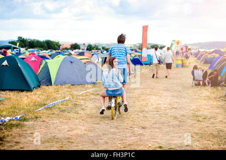 Teenage couple riding bike together at summer music festival Stock Photo