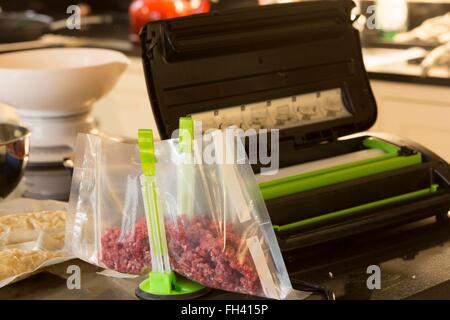 Preparing food for the freezer at home using a vacuum sealer to keep the meat (beef in this case) fresh. Stock Photo