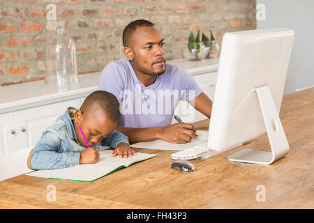 Cute son doing his homework with father Stock Photo