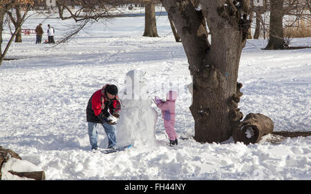 Father and young daughter build a snowman together in Prospect Park, Brooklyn, NY. Stock Photo