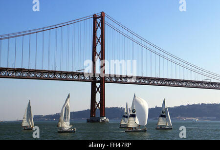 Lisbon, Portugal. 14th Dec, 2015. Sailing boats from the BMW Sailing Academy on the river Tagus in front of the Ponte 25 de Abril bridge in Lisbon, Portugal, 14 December 2015. The bridge is the world's second-longest suspension bridge, after the Tsing Ma Bridge in Hong Kong, and carries both road and rail traffic. Photo: Hauke Schroeder/dpa/Alamy Live News Stock Photo