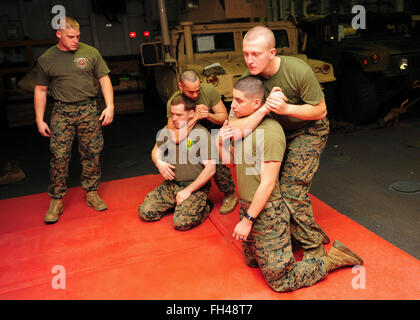 PACIFIC OCEAN (Feb. 22, 2016) Marines assigned to the 13th Marine Expeditionary Unit (13th MEU) practice a rear chokehold move during Marine Corps Martial Arts Program training in the lower vehicle deck aboard amphibious assault ship USS Boxer (LHD4). More than 4,500 Sailors and Marines from Boxer Amphibious Ready Group and the 13th Marine Expeditionary Unit (13th MEU) are conducting sustainment training off the coast of Hawaii in preparation for entering the U.S. 5th and 7th Fleet areas of operations Stock Photo