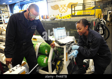 PACIFIC OCEAN (Feb. 22, 2016) Aviation Support Equipment Technician Airman Jamecia Shaw gives instructions to Aviation Support Equipment Technician Airman Malik Thomas during a hydraulic contamination test in the hanger bay aboard amphibious assault ship USS Boxer (LHD4). More than 4,500 Sailors and Marines from Boxer Amphibious Ready Group and the 13th Marine Expeditionary Unit (13th MEU) are conducting sustainment training off the coast of Hawaii in preparation for entering the U.S. 5th and 7th Fleet areas of operations Stock Photo