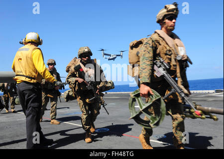 PACIFIC OCEAN (Feb. 22, 2016) Marines assigned to the 13th Marine Expeditionary Unit (13th MEU), disembark a helicopter on the flight deck of amphibious assault ship USS Boxer (LHD4) while an MV-22 Osprey prepares to land. More than 4,500 Sailors and Marines from Boxer Amphibious Ready Group and the 13th Marine Expeditionary Unit (13th MEU) are conducting sustainment training off the coast of Hawaii in preparation for entering the U.S. 5th and 7th Fleet areas of operations Stock Photo