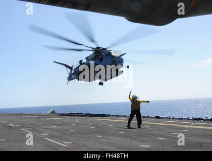 PACIFIC OCEAN (Feb. 22, 2016) Aviation Boatswain’s Mate Airman Nicholas Ballard-Henry directs a CH-53 Sea Stallion as it takes off from the flight deck of amphibious assault ship USS Boxer (LHD4). More than 4,500 Sailors and Marines from Boxer Amphibious Ready Group and the 13th Marine Expeditionary Unit (13th MEU) are conducting sustainment training off the coast of Hawaii in preparation for entering the U.S. 5th and 7th Fleet areas of operations Stock Photo
