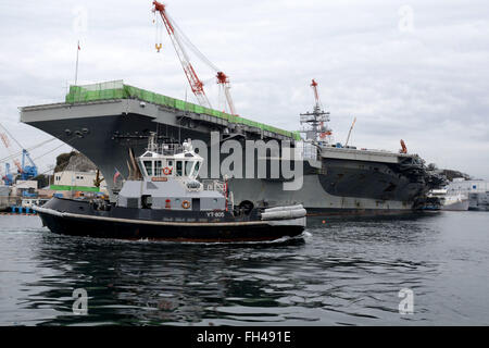 YOKOSUKA, Japan (Feb. 22, 2016) The Valiant-class yard tugboat USS Seminole (YT 805) passes the U.S. Navy’s only forward-deployed aircraft carrier, USS Ronald Reagan (CVN 76), currently moored pier-side at Fleet Activities (FLEACT) Yokosuka. FLEACT Yokosuka provides, maintains, and operates base facilities and services in support of 7th Fleet's forward-deployed naval forces, 83 tenant commands, and 24,000 military and civilian personnel. Stock Photo