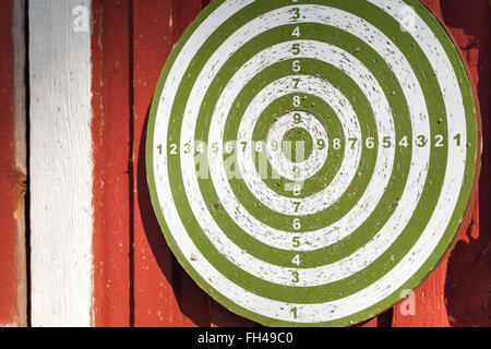 Old darts target hanging on red wooden wall Stock Photo