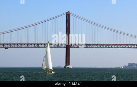 Lisbon, Portugal. 14th Dec, 2015. A sailing boat on the river Tagus in front of the Ponte 25 de Abril bridge in Lisbon, Portugal, 14 December 2015. The bridge is the world's second-longest suspension bridge, after the Tsing Ma Bridge in Hong Kong, and carries both road and rail traffic. Photo: Hauke Schroeder - NO WIRE SERVICE -/dpa/Alamy Live News Stock Photo