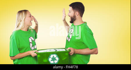 Composite image of smiling volunteer doing high five while holding container Stock Photo