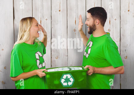 Composite image of smiling volunteer doing high five while holding container Stock Photo
