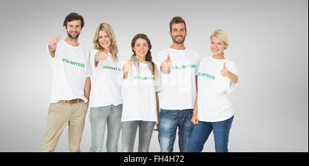 Composite image of group portrait of happy volunteers gesturing thumbs up Stock Photo