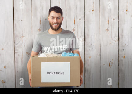 Composite image of portrait of man holding clothes donation box in office Stock Photo