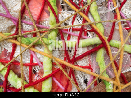 Abstract pattern of one above the other wound, colorful wool threads combined with fabrics and bright lace Stock Photo