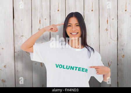 Composite image of smiling woman pointing to her volunteer tshirt Stock Photo