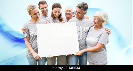 Composite image of happy volunteer family holding a blank Stock Photo