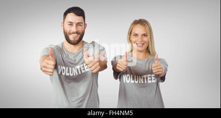 Composite image of smiling volunteers giving thumbs up Stock Photo