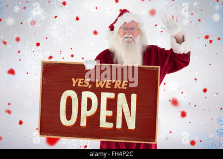 Composite image of santa holds a sign and is waving Stock Photo