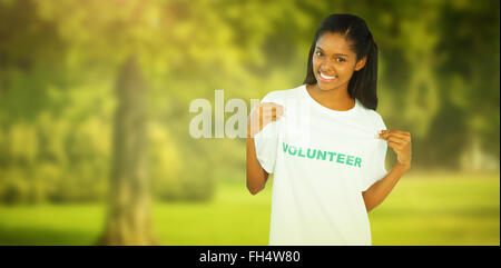 Composite image of young woman wearing volunteer tshirt and pointing to it Stock Photo