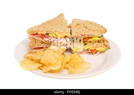 Brown bread ham salad sandwich with potato crisps on a plate isolated against white Stock Photo