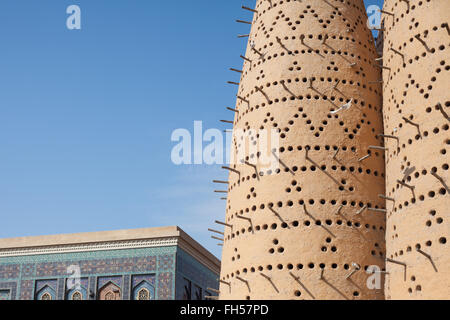 The roof of Katara Masjid and a dove flying from a perch on the traditional arabian dovecotes or pigeon towers Stock Photo