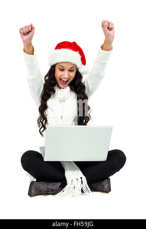 Woman sitting on the floor rejoicing looking at laptop Stock Photo