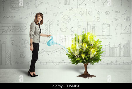 Business woman pouring water on lightbulb growing tree Stock Photo
