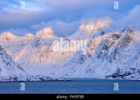 Mountains covered in snow at sunset in winter, viewed from the Spellmannsbukta to Kunna Island and Flakstadoya, Lofoten, Norway Stock Photo