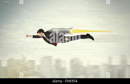 Superhero business man flying with jet pack rocket above the city Stock Photo