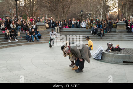 Street performance in Washington Square Park of acrobat somersaulting over volunteers with crowds of spectators Stock Photo