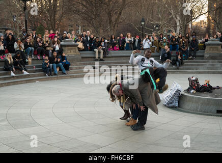 Street performance in Washington Square Park of acrobat somersaulting over volunteers with crowds of spectators Stock Photo