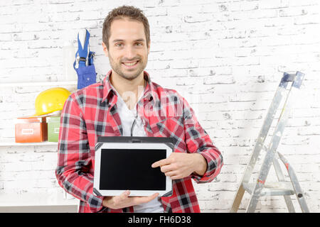 a smiling young carpenter showing the screen on digital tablet Stock Photo