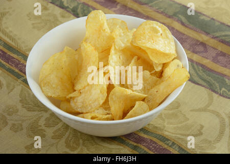 Potato chips in white bowl on table Stock Photo