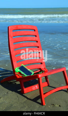 red little chair on the beach with a smartphone closed in the protective waterproof Stock Photo