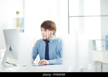 Contemporary businessman looking at monitor in office Stock Photo