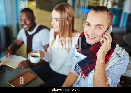Smiling guy talking on the phone on background of friends Stock Photo