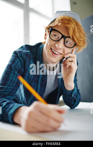 Handsome young architect speaking on the phone while drawing sketch Stock Photo