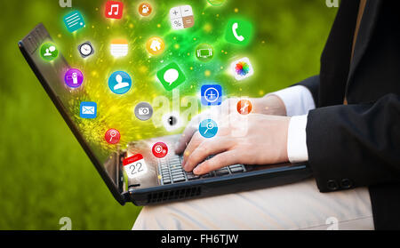 Hand pressing modern laptop with mobile app icons and symbols Stock Photo