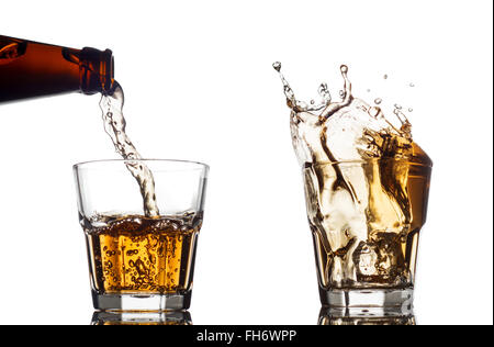 Pouring whiskey in a clear glass, on white background Stock Photo