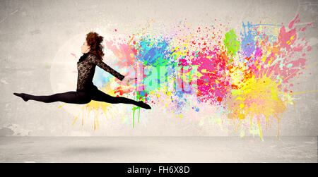 Happy teenager jumping with colorful ink splatter on urban background Stock Photo