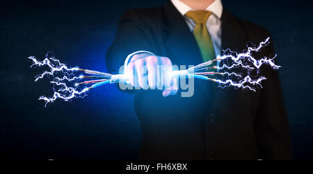 Business person holding electrical powered wires Stock Photo