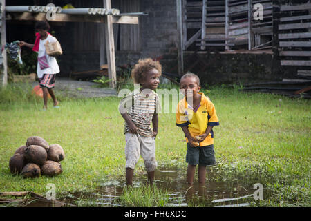 Batuna, Solomon Islands - May 28, 2015: Two boys are playing in a puddle of water at the local market in Batuna village. Stock Photo