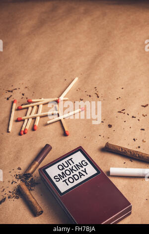 Quit smoking today concept, warm retro toned image of ashtray, pack of cigarettes, a lighter, matches and broken cigarette on ta Stock Photo