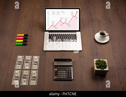 Computer desk with laptop and red arrow chart in screen Stock Photo