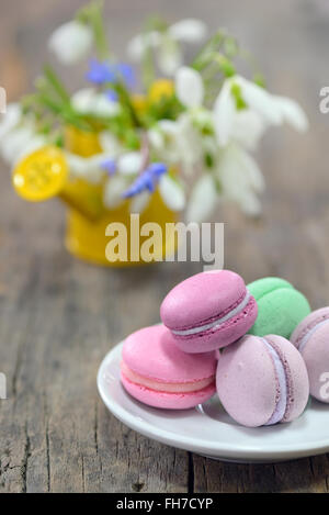 Colorful French Macarons and spring flowers on wooden background Stock Photo