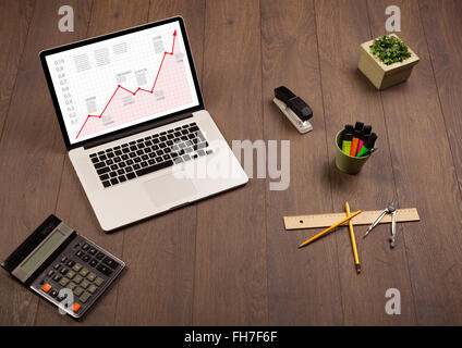 Computer desk with laptop and red arrow chart in screen Stock Photo