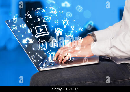 Hand writing on notebook computer with media icons and symbols Stock Photo