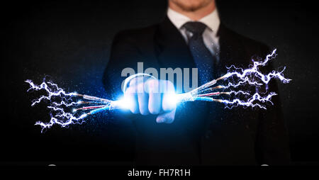 Business person holding electrical powered wires Stock Photo