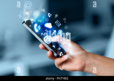 Business man holding smart phone with media icons Stock Photo