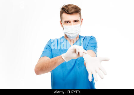 Male surgeon in mask putting on gloves isolated on a white background Stock Photo