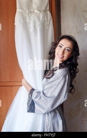 Beautiful bride in the morning of wedding day with her dress trying Stock Photo